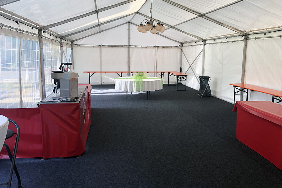 Innenansicht eines Event-Zelts von Pilz Zelte und Planen, blick auf die mit roter Plane abgedeckte Theke und die Tanzfläche aus Teppichboden