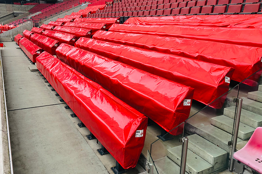 Tribüne eines Fußballstadions mit abgedeckten Sitzplätzen unter einer roten Abdeckplane von Pilz Zelte und Planen