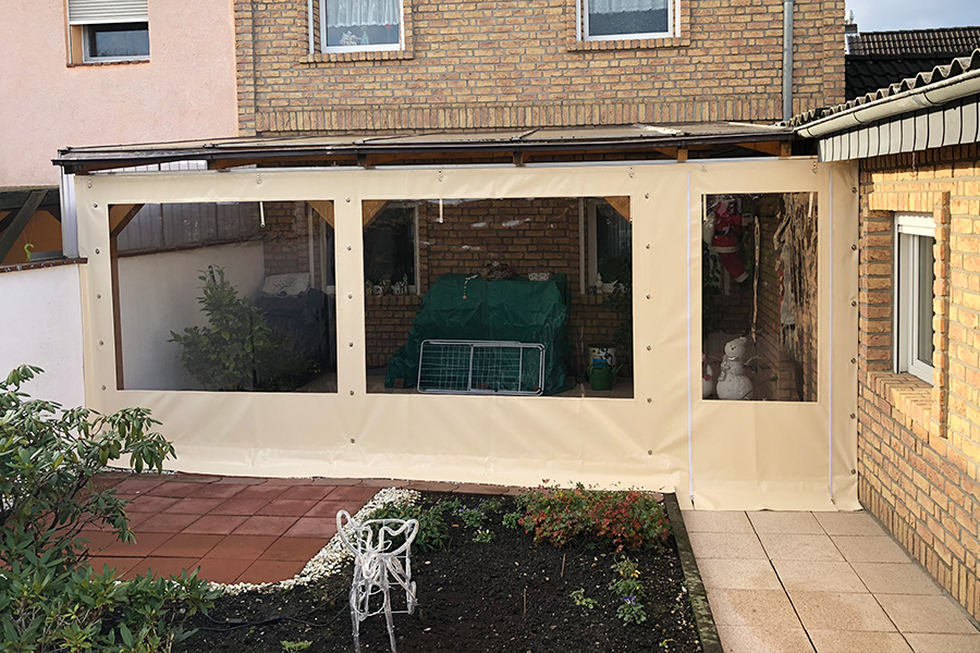 Blick auf überdachte Terrasse im Garten eines Wohnhauses mit einer PVC-Plane aus dem Hause Pilz Zelte und Planen