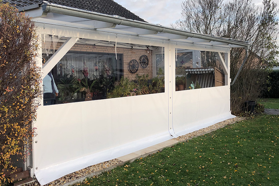 Außenansicht eines Wintergarten-Anbaus aus weißem PVC an ein Wohnhaus im Gartenbereich