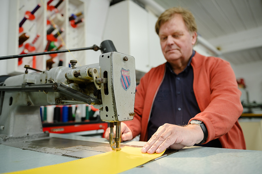 Horst Pilz in Werkstatt  bei der Arbeit an mit der Nähmaschine an einer gelben Folie